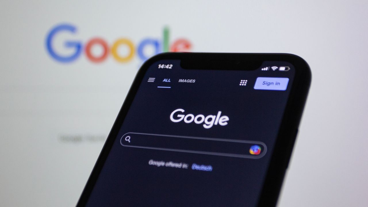 services-04 Smartphone screen displaying a Google search in dark mode, with the Google logo visible in the background.